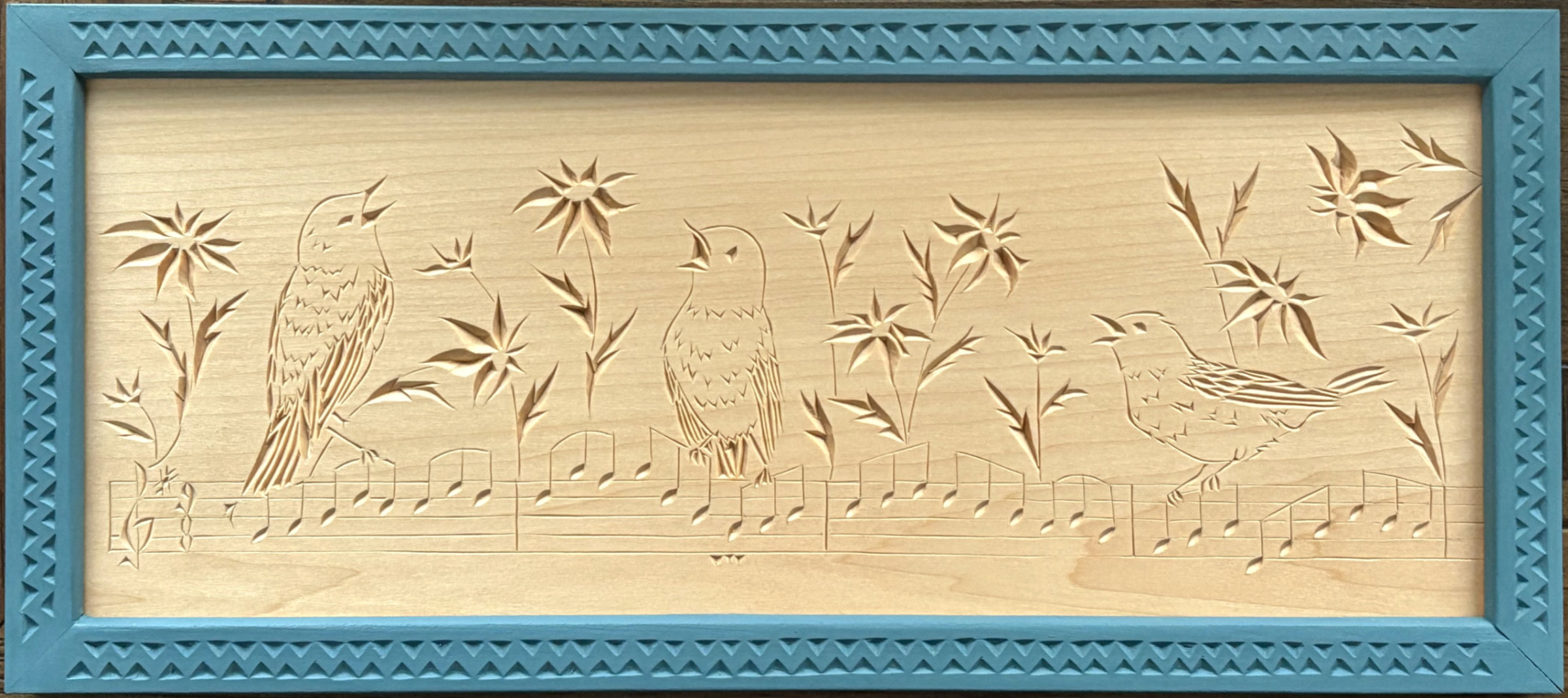 chip carving of singing birds and flowers adorning a staff of music